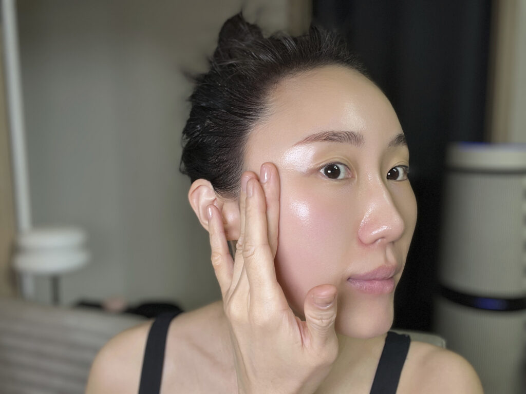Massaging base prep into skin with fingertips for a dewy finish